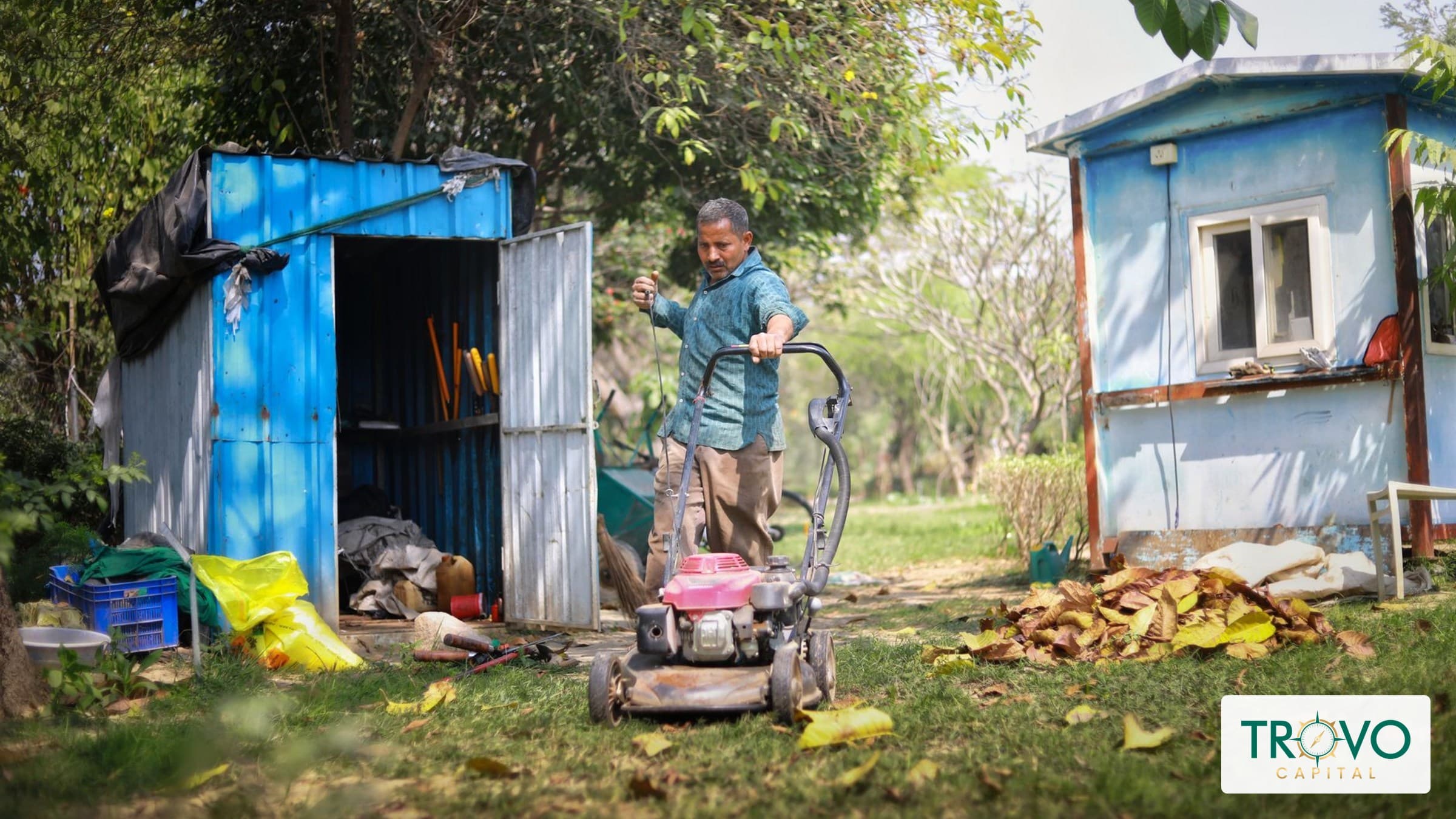 Landscaping business owner inspecting a commercial mower outside an equipment shed