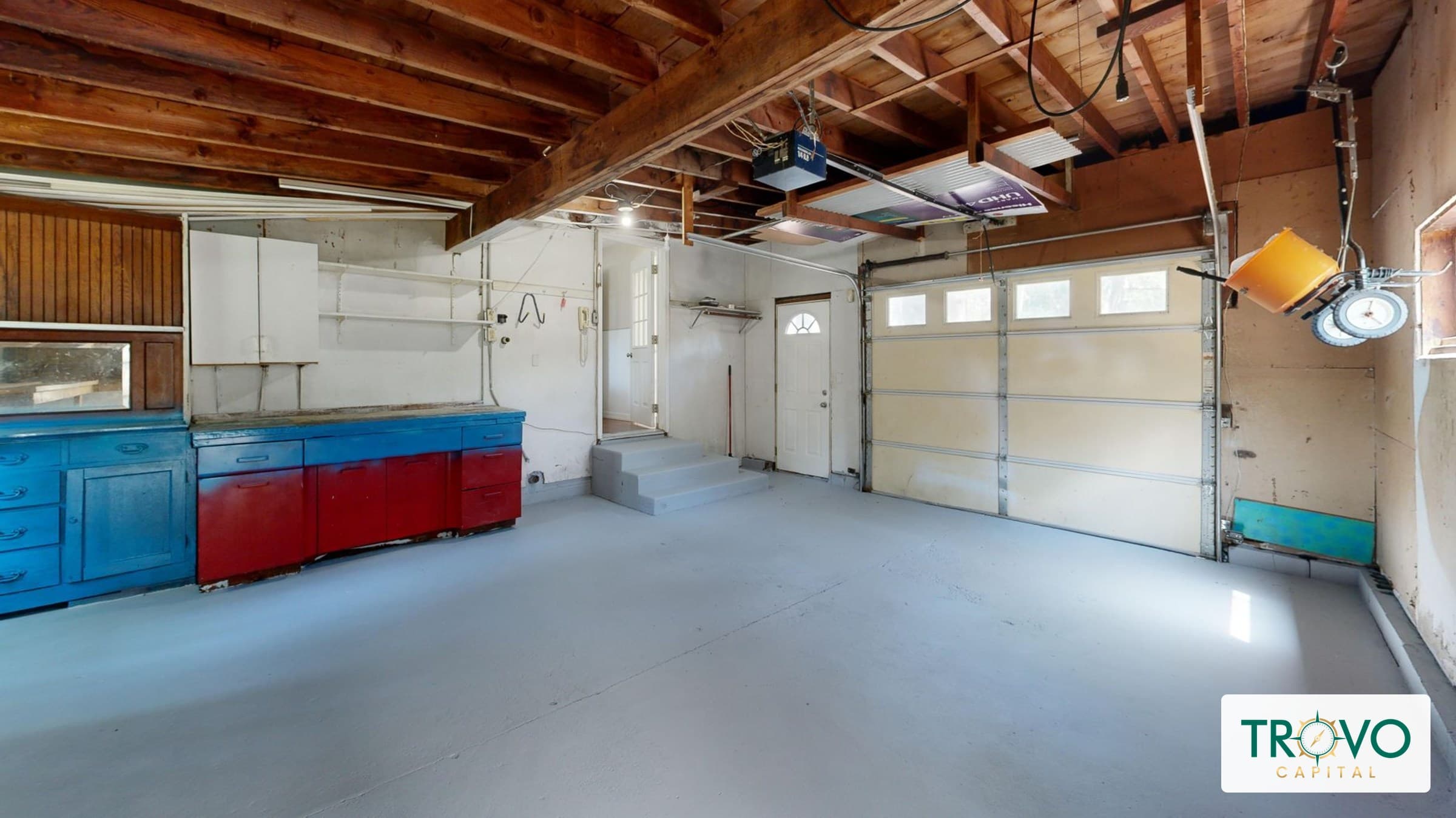 A furniture maker working in a modest home garage workshop beside a residential entryway.