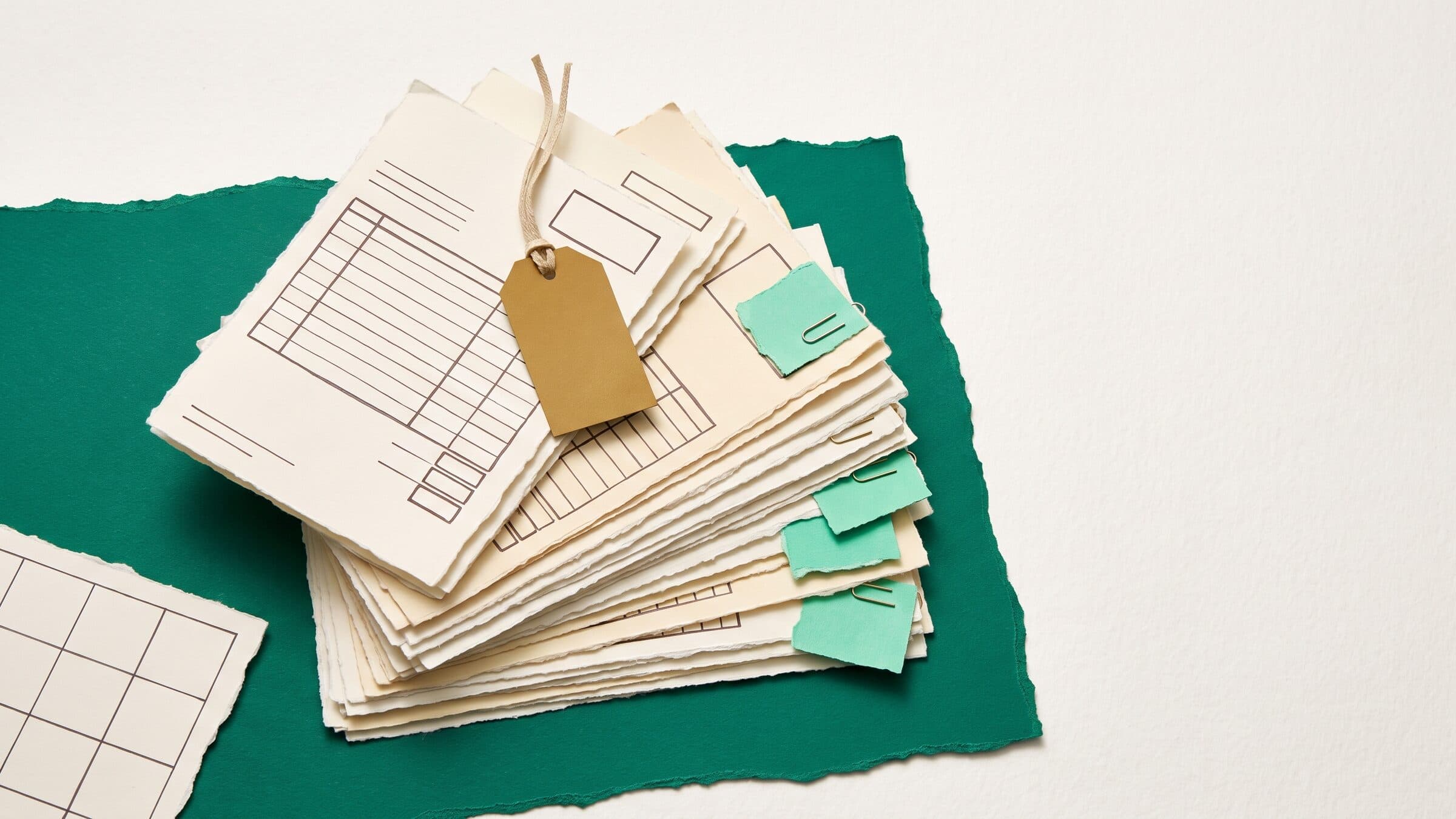 Paper collage of a stack of blank invoices on emerald paper, most with mint tags and one pulled out wearing a gold overdue tag