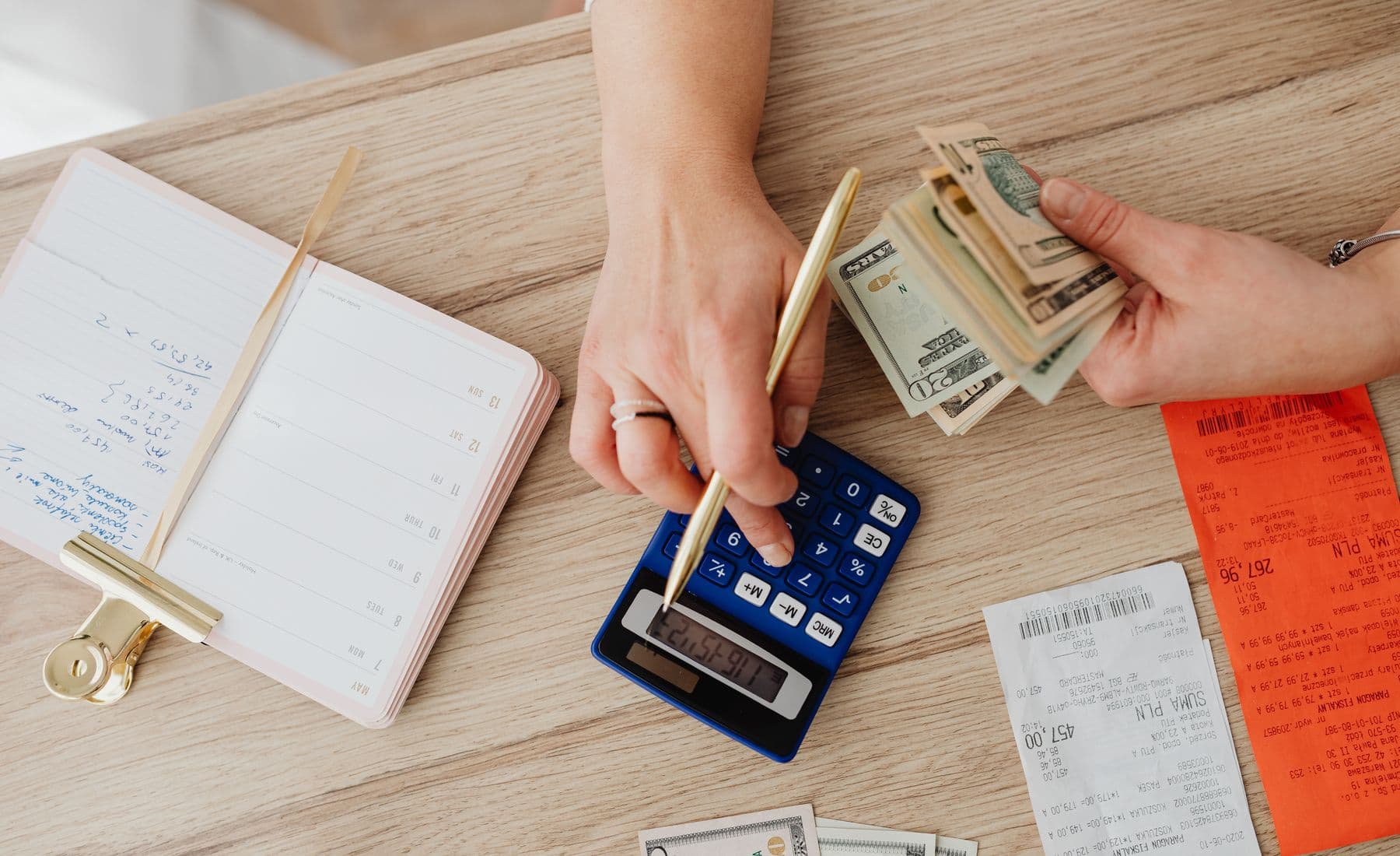 Hands budgeting with cash, receipts, and a calculator.