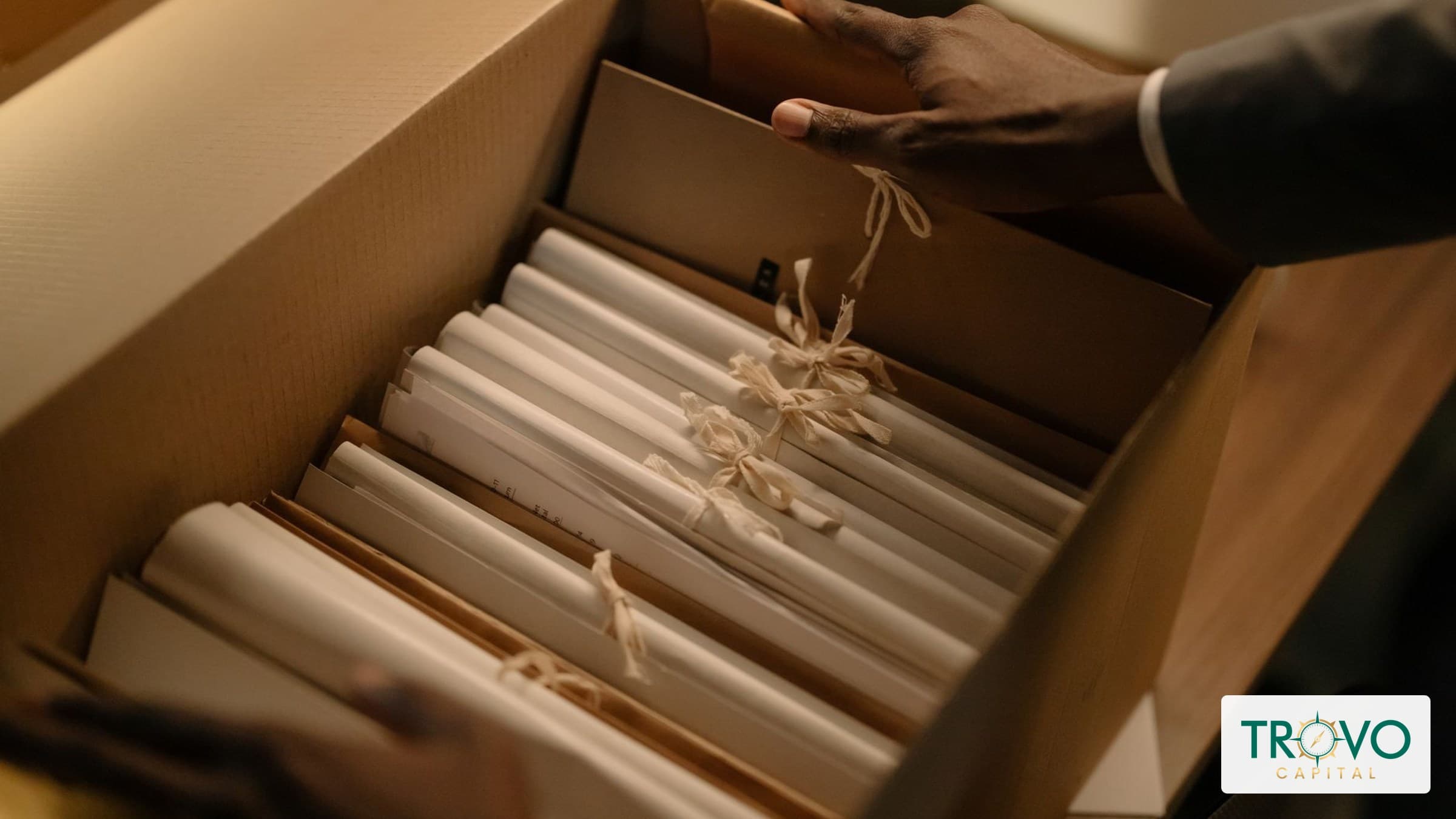 Overhead view of hands organizing archived loan records and correspondence beside an open file box.
