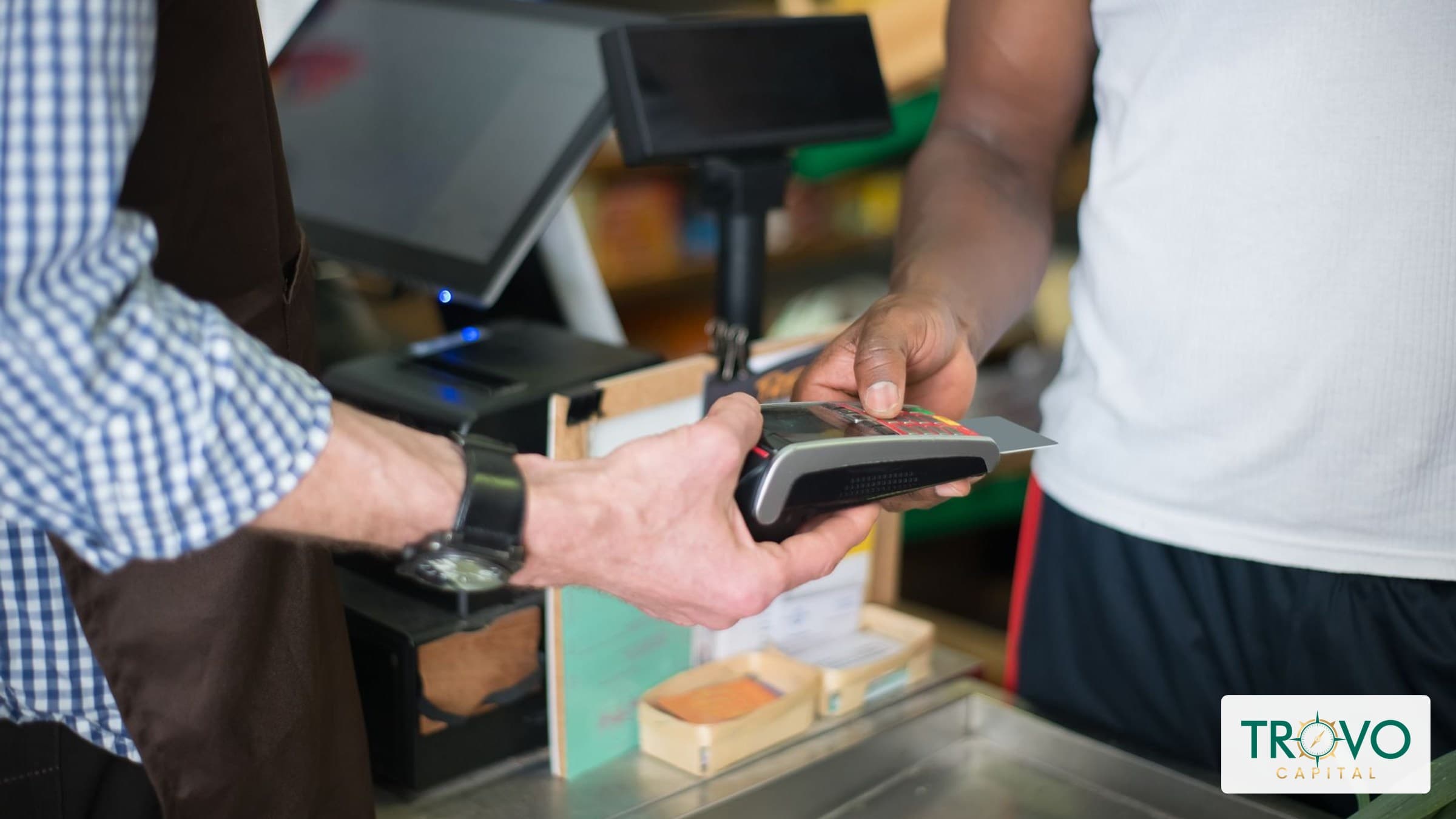 Hardware store employees testing a handheld payment reader beside an idle countertop terminal.